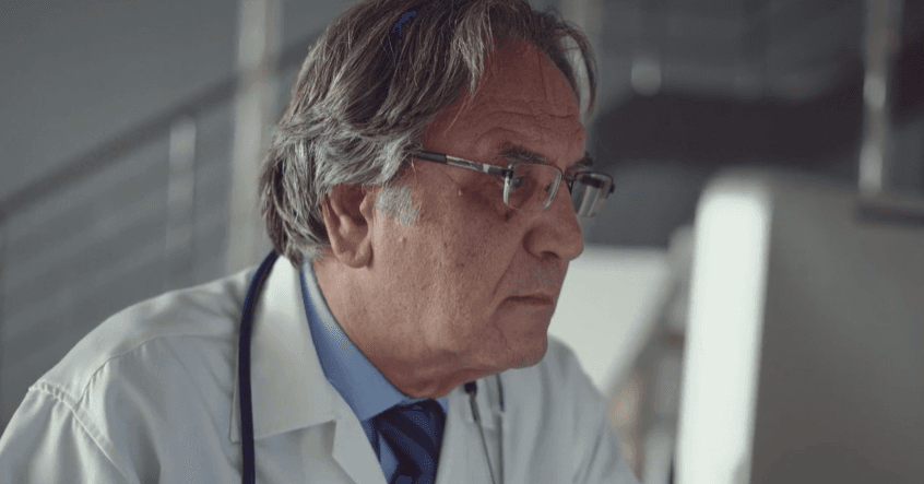 Senior physician focused on a computer screen, close-up